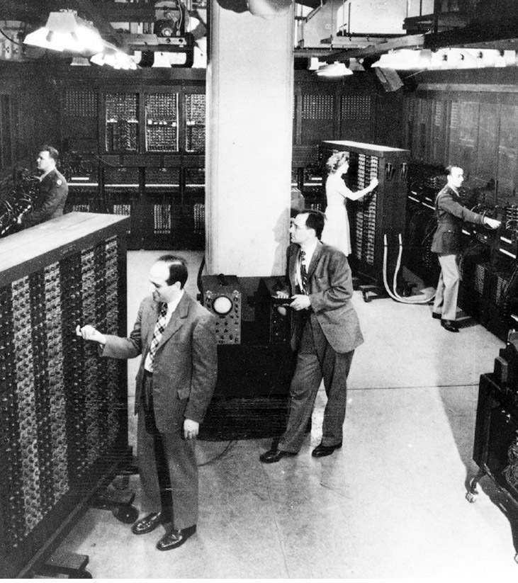 Eckert (touchant la machine), Mauchly (près du pilier), Jean Jennings (au fond) et Herman Goldstine (à côté de J. Jennings) avec l’ENIAC en 1946.